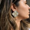 Model wearing grey geometric hand-embroidered statement earrings