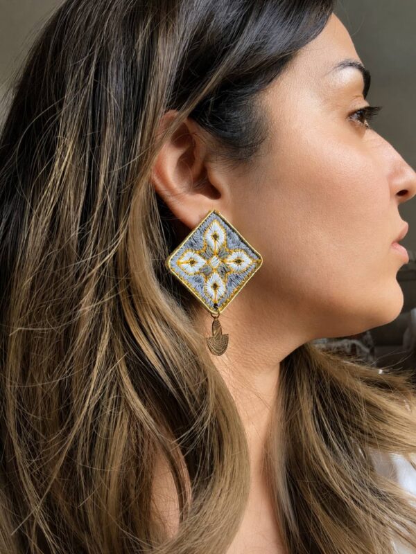 Model wearing grey geometric hand-embroidered statement earrings