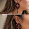 Model wearing red and green floral embroidered earrings with tassels