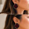 Model wearing red and navy geometric embroidered earrings with tassels