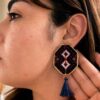 Model wearing white double-diamond embroidered earrings with navy tassels