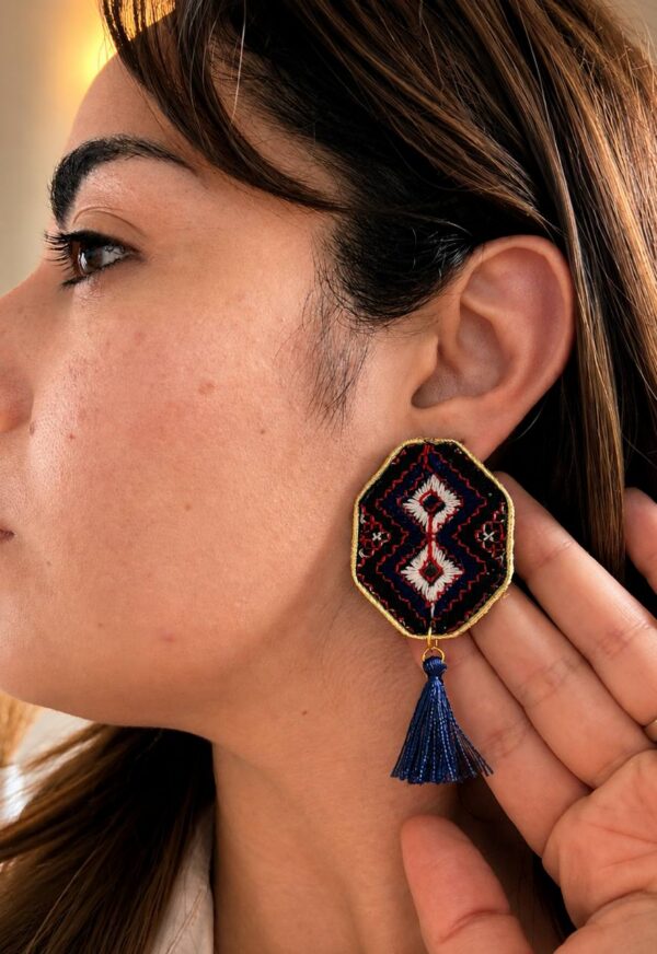 Model wearing white double-diamond embroidered earrings with navy tassels