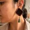 Model wearing red and green diamond embroidered earrings with tassels
