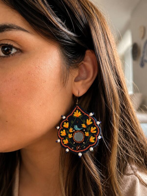 Model wearing yellow floral and blue bird embroidered earrings