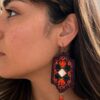 Model wearing orange floral embroidered earrings with red bead drops
