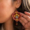Model wearing red embroidered earrings with yellow flowers and red bead drops
